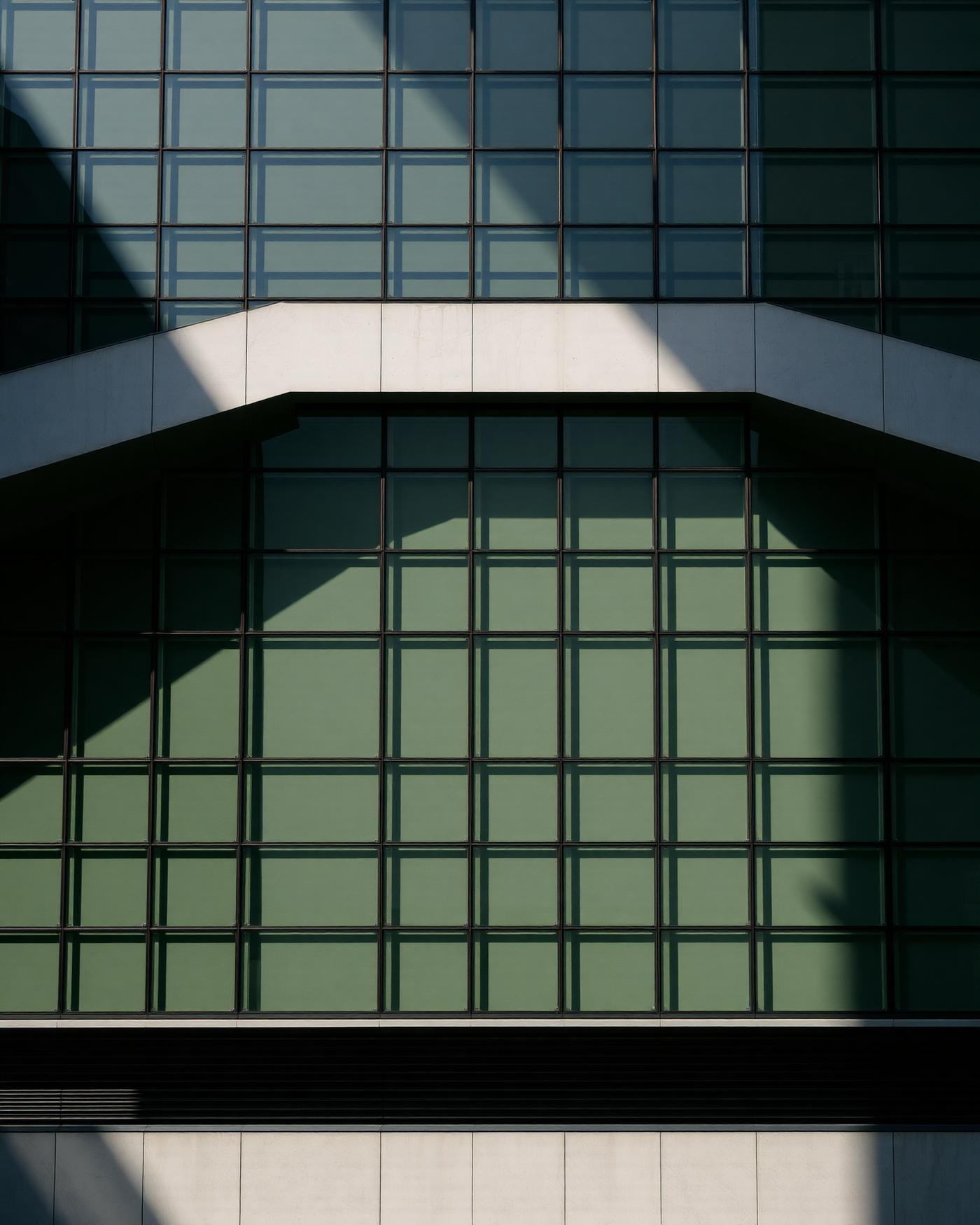 Geometric grid facade of a modern office building lit by sharp morning sunlight